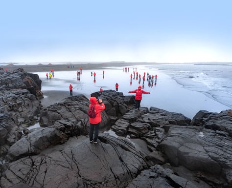 Touristen der Kreuzfahrt am Reynisfjara Strand in Island. Ein wirklich beliebter Fotospot wegen dem schwarzen Sandstrand